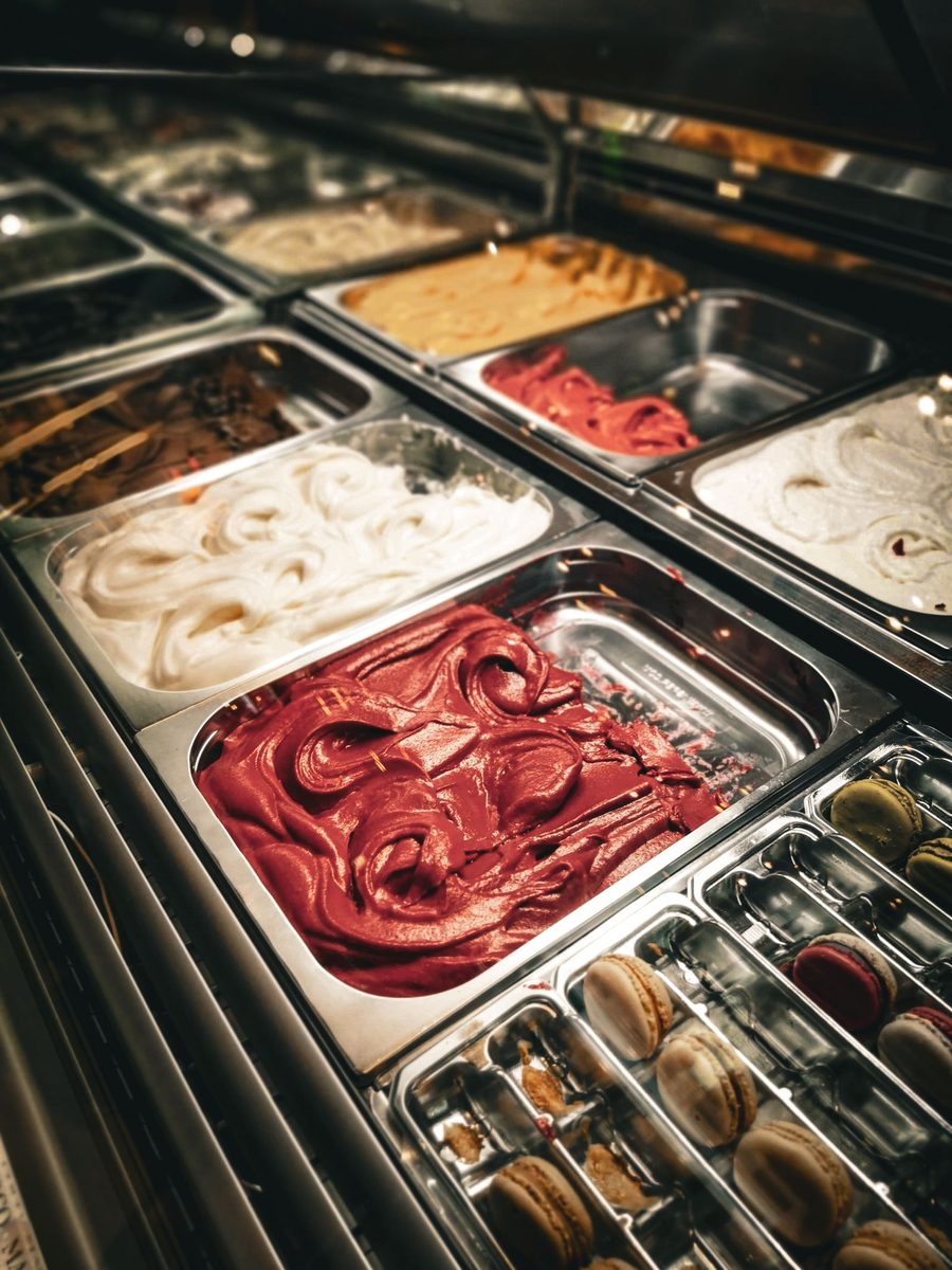 Trays of ice cream in a lit display case, cream and deep red side by side.