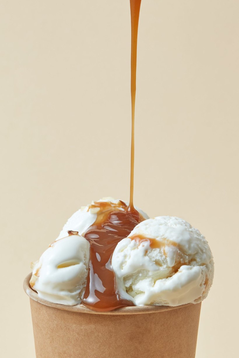 Sauce poured over two scoops of ice cream in a paper cup.