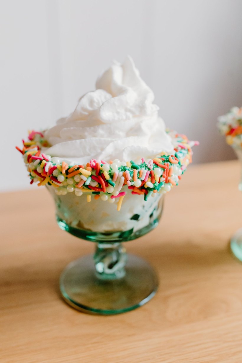 A coupe glass of ice cream with whipped cream and a thick rim of sprinkles.
